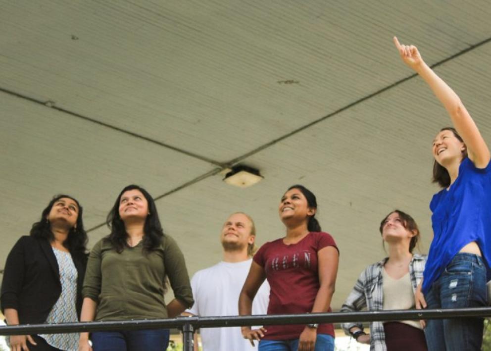 Dr. Hartley standing and pointing at something while the rest of the members look