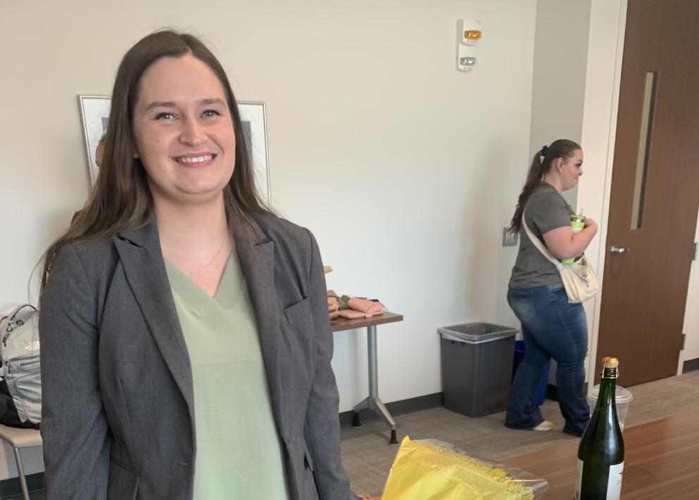 Woman smiles in conference room next to cake