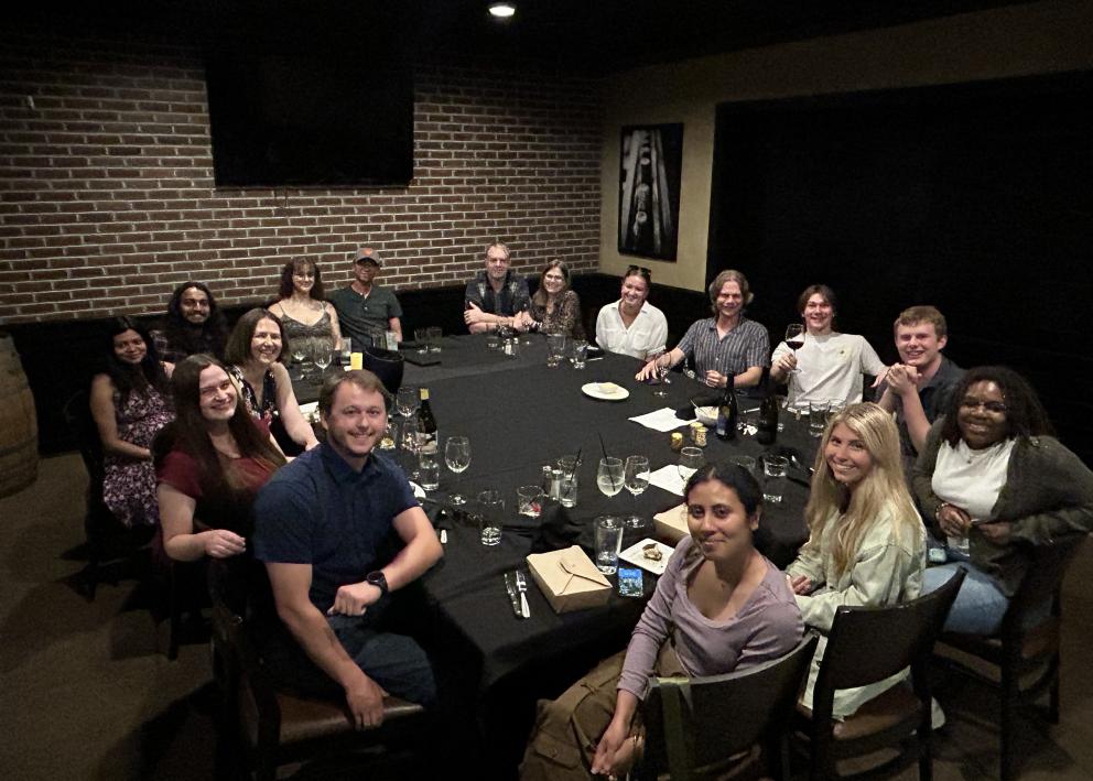 Group of people sit around a square table at a restaurant