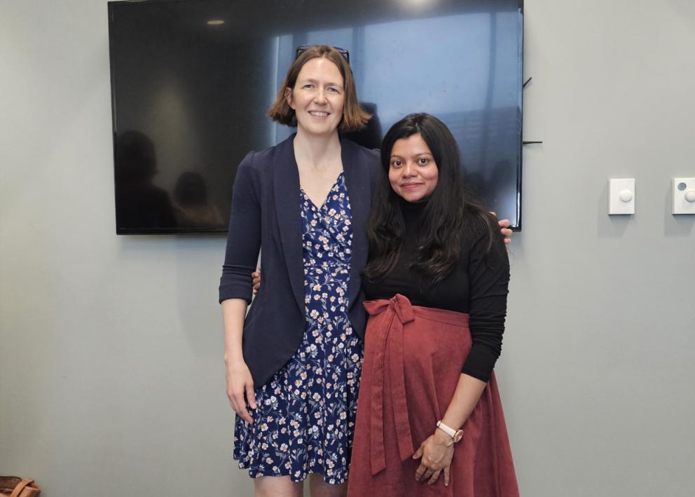Two women in front of cake in conference room