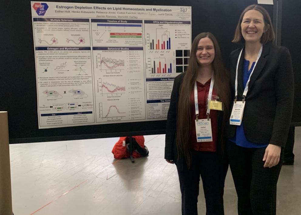 Two women stand by poster