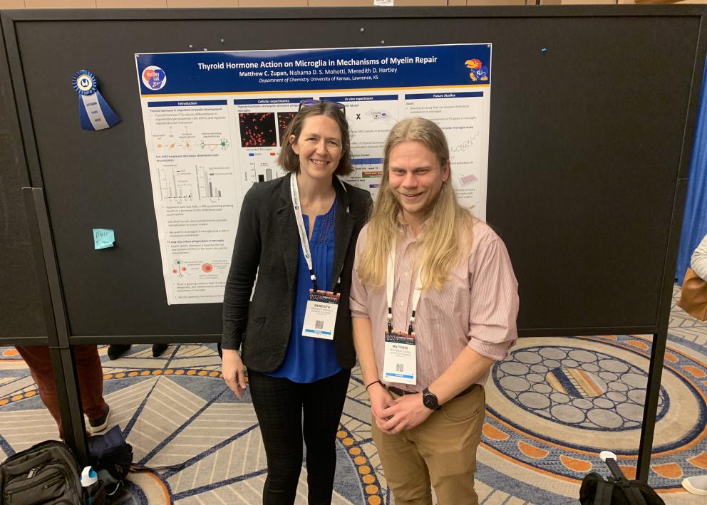 Two people smile in front of a scientific poster