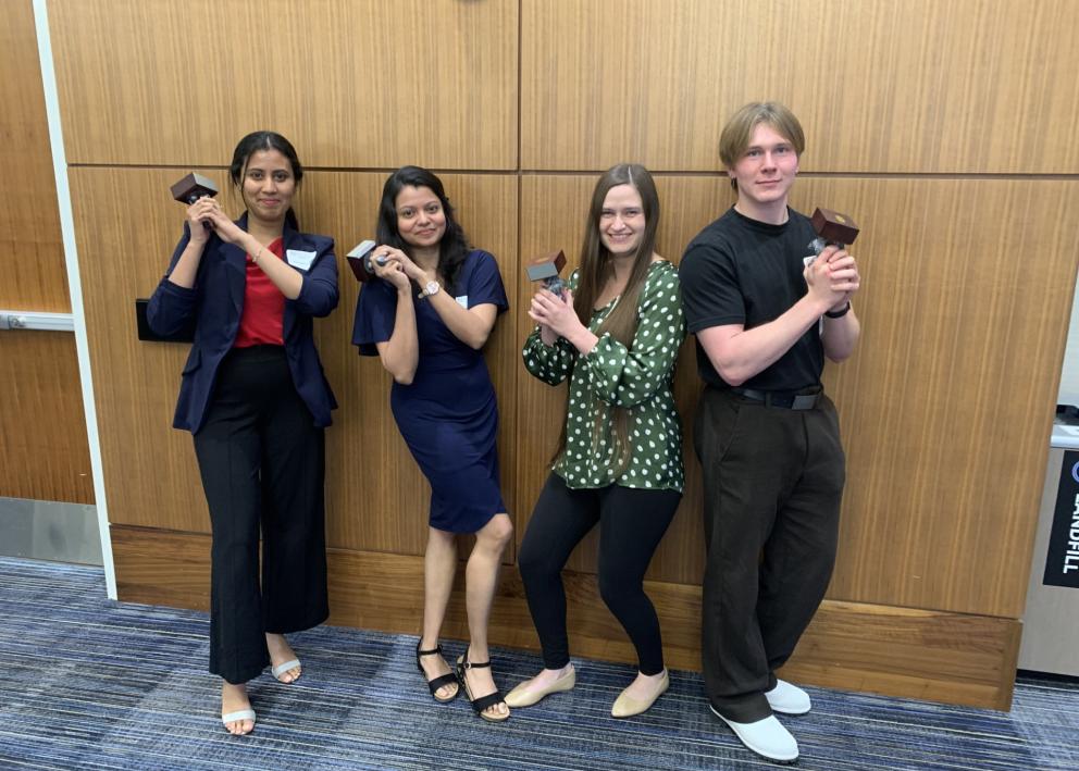 Four students pose like Charlie's Angels holding statues