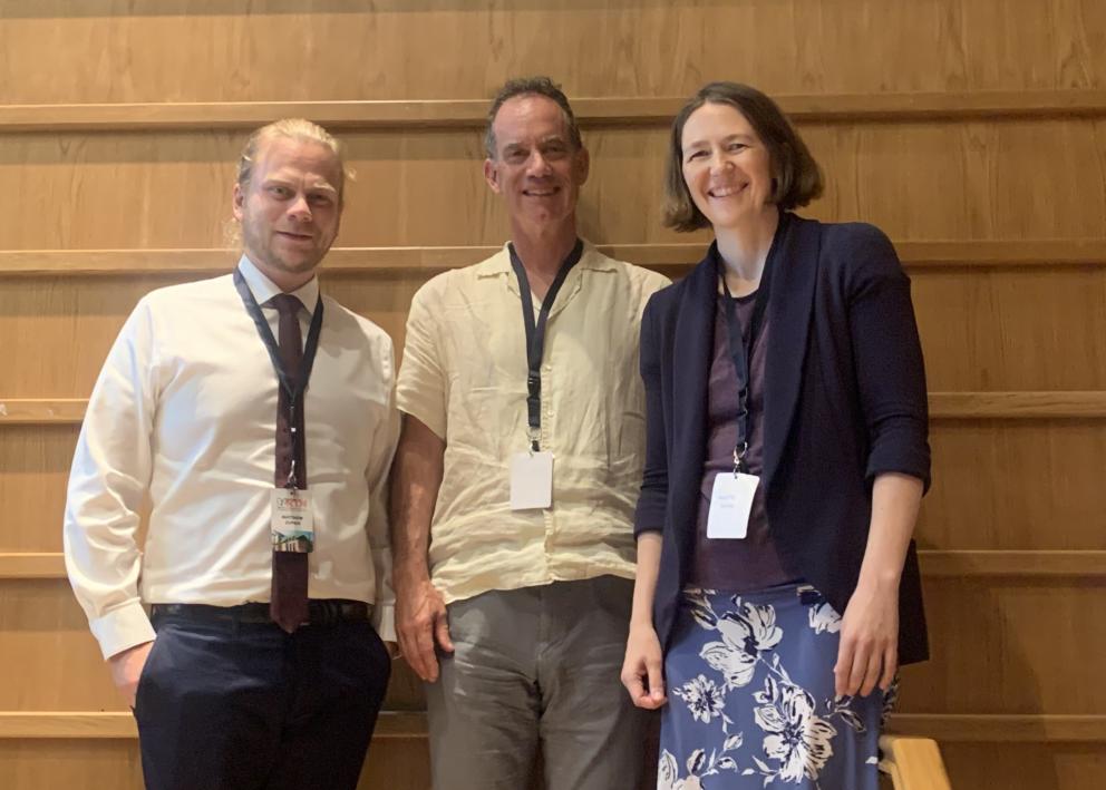 Three people smile wearing conference lanyards