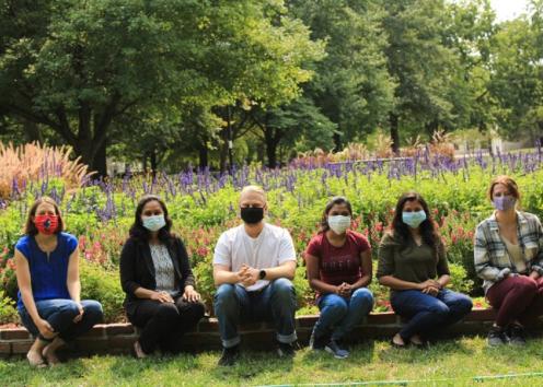 Group members sitting down for a picture with each one having a their mask on