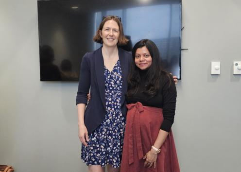Two women in front of cake in conference room