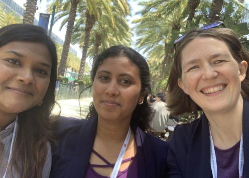 Three women take a selfie with palm trees in the background