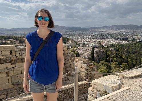 Woman stands in front of city view with mountains in the background