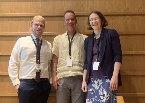 Three people smile wearing conference lanyards