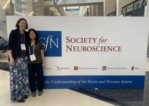 Two people pose in front of Society for Neuroscience large sign