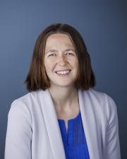 Woman smiling in blue shirt and gray blazer